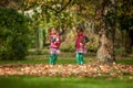 Identical twins having fun with toys and leaves in autumn in the park, blond cute curly girls, happy girls,beautiful girls in pink Royalty Free Stock Photo