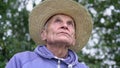 Identity close video portrait of old sad farmer in big strawy hat.