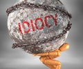 Idiocy and hardship in life - pictured by word Idiocy as a heavy weight on shoulders to symbolize Idiocy as a burden, 3d