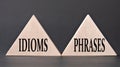 IDIOMS and PHRASES - words on wooden triangles on dark background