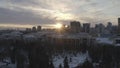 Idyllic aerial view of modern city buildings, park and church at the sunset in winter. Action. City winter landscape