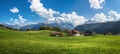 Idyllic alpine landscape with green meadows, farmhouses and snow-capped mountain tops Royalty Free Stock Photo