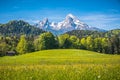 Idyllic alpine landscape with green meadows, farmhouses and snowcapped mountain tops Royalty Free Stock Photo