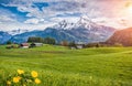 Idyllic alpine landscape with green meadows, farmhouses and snowcapped mountain tops Royalty Free Stock Photo