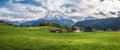 Idyllic alpine landscape with green meadows, farmhouses and snowcapped mountain tops Royalty Free Stock Photo