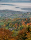 Idyllic autumn landscape with colorful leaves on the trees, with small terrace fields, village houses and fog in the background. Royalty Free Stock Photo