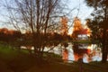 Idyllic autumn landscape with a cottage surrounding by golden trees and beautiful lake