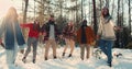 Idyllic cinematic slow motion, happy fun multiethnic friends throw snow up smiling in sunny winter forest slow motion.