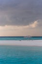 An idyllic island in Maldive in a stormy weather afternoon. Super clear water, white sand, traditional huts and tropical climate f