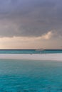 An idyllic island in Maldive in a stormy weather afternoon. Super clear water, white sand, traditional huts and tropical climate f