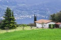 Idyllic Italian rural landscape green lawn, conifers, nebolshoy the white house with tiled roof in the background is lake Garda