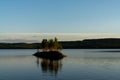 Idyllic lake landscape with a small island with trees under a cloudless blue sky Royalty Free Stock Photo