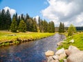 Idyllic landscape with calm mountain river on sunny day. White stones and green meadows and trees. Sumava National Park Royalty Free Stock Photo