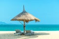 Idyllic landscape paradise scene at the beach with strawy loungers on clear blue sky day