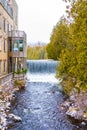 Idyllic natural landscape, waterfall of a river near building with balconies