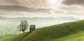 Idyllic and peaceful mountain landscape with a secluded wooden barn and lone tree on a grassy hillside and a great view of the Swi