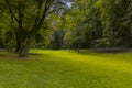 Idyllic peaceful park outdoor nature scenic spring time environment green grass meadow smooth ground surface surrounded by trees f