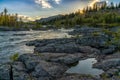 Idyllic river and pine forest landscpe with a setting sun and sun star and a heart-shaped pool in the foreground Royalty Free Stock Photo