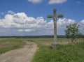 Idyllic rural landscape with old stone cross with Jesus Christ s