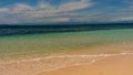 Idyllic sandy tropical beach at Bocas Del Toro, Panama with a calm blue ocean gently lapping the shore under a cloudy blue sky, a