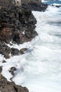 Idyllic scene of clear blue sea crashing against volcanic black rocks at cliffs of Terceira Island, Azores.
