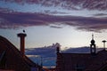 Sunset scenery over rooftops with White stork resting in nest on chimney