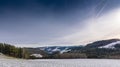 Idyllic snowy hilly countryside panorama, blue sunny sky