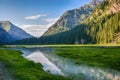 Idyllic summer landscape with hiking trail in the mountains with beautiful fresh green mountain pastures, river with reflection