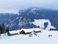 Idyllic Swiss alpine mountain huts dressed in winter clothes and in a fresh snow cover on slopes on the Alpstein mountain range