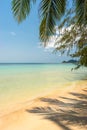 Idyllic tropical sandy beach in sunny day. Palm leaves shadow, calm ocean wave on shore, clear turquoise sea water Royalty Free Stock Photo