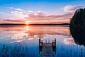 Idyllic view of the long pier with wooden bench on the lake. Sunset or sunrise over the water Royalty Free Stock Photo