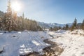 Sunny winter landscape in the alps: Mountain range, river, snowy trees, sunshine and blue sky Royalty Free Stock Photo