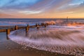 Idyllic wooden dock leading into the ocean waves at a peaceful sunset