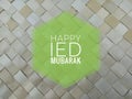 Ied mubarak. Happy Ied Mubarak card on blurry background of  natural palm leaf mat. Royalty Free Stock Photo