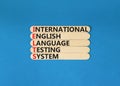 IELTS symbol. Concept words IELTS international english language testing system on wooden stick. Beautiful blue background. Royalty Free Stock Photo