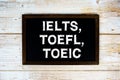 IELTS, TOEFL, TOEIC text with gift box present and alarm clock on black background Royalty Free Stock Photo