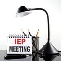 IEP MEETING text on notebook with pen and table lamp on the black background Royalty Free Stock Photo