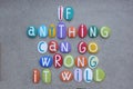 If anything can go wrong, it will, creative quote composed with multi colored stone letters over green sand