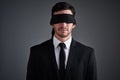 If I didnt see it, did it happen. Studio shot of a young businessman wearing a blindfold against a gray background.