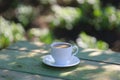 A cup of coffee with milk on a garden wooden table