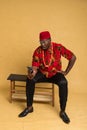 Igbo Traditionally Dressed Business Man Sitting Down and Staring at Phone in shock Royalty Free Stock Photo