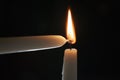 Ighting tall candle with another candle in the dark Royalty Free Stock Photo
