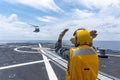 Signal man gives the hand signal to Sikorsky MH-60S Seahawk helicopter to land on the flight deck of the HTMS. Bhumibol Adulyadej