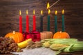 Ignition of Kwanzaa traditional candles, holiday concept with gift box, pumpkins, ears of wheat, grapes, corns, banana, bowl and Royalty Free Stock Photo