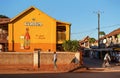 Ihosy, Madagascar - May 05, 2019: Local Malagasy man walking in front of large hand painted Castel beer ad on orange house wall,