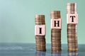 IHT - acronym on wooden cubes on stacks of coins Royalty Free Stock Photo