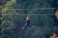 Fun, adrenaline and adventure on the zip line. Teenager having fun on a zipline on panoramic forest background Royalty Free Stock Photo