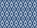 Ikat pattern as ethnic fabric in blue tone with switching circle and diamond design. Wallpaper seamless pattern design in blue. Royalty Free Stock Photo