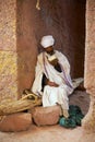 Ilgrim reads bible at the entrance to the unique monolithic rock-hewn church in Lalibela, Ethiopia. UNESCO World Heritage site.