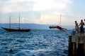 Young man jumping from the pier into the water ocean at sunset. Wearing swimsuits with friends Royalty Free Stock Photo